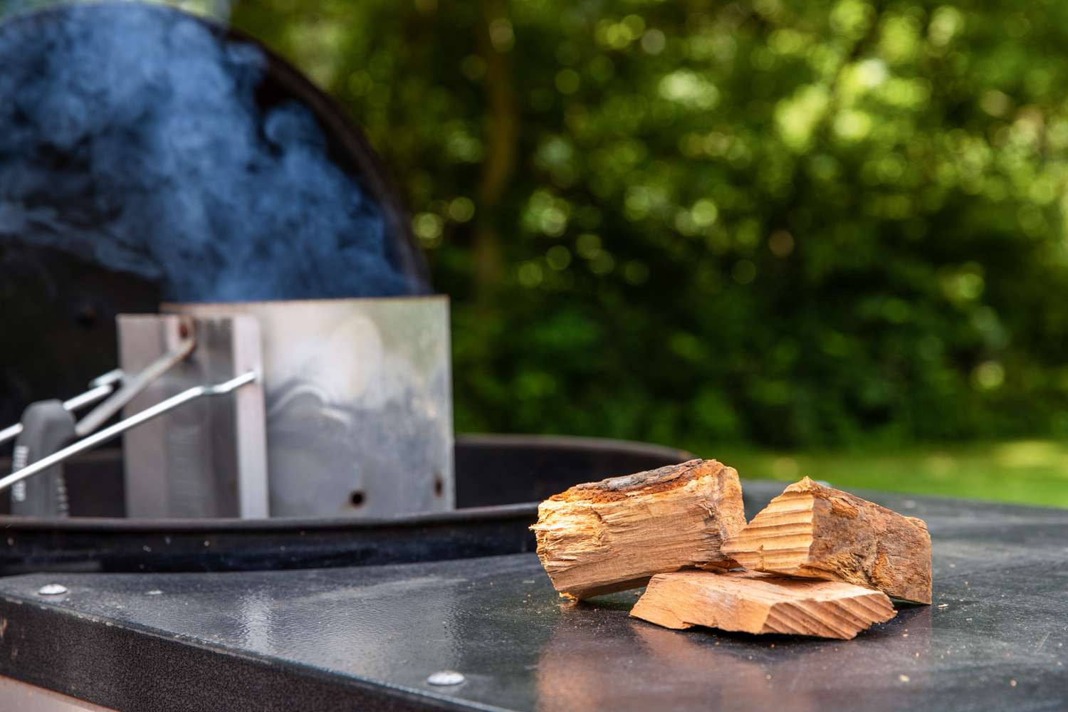 A charcoal chimney and chunks of pecan wood outside to smoke make a smoked turkey.