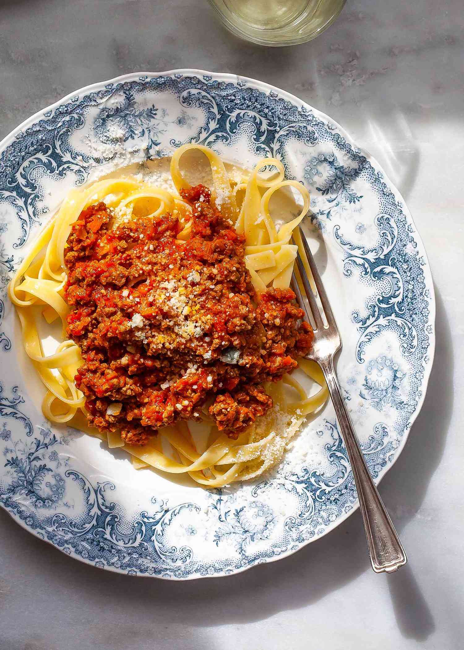 The best bolognese sauce poured over on top of noodles with a fork on the side.