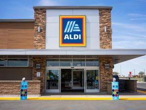 Front entrance and sign of an Aldi grocery store with a mostly clear blue sly above