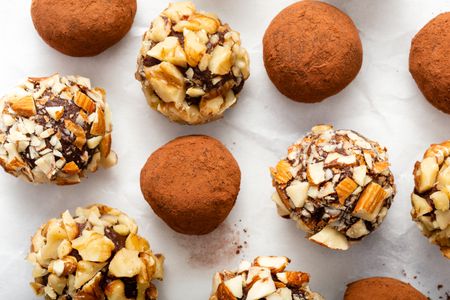 Overhead view of chocolate truffles covered in cocoa and chopped nuts.