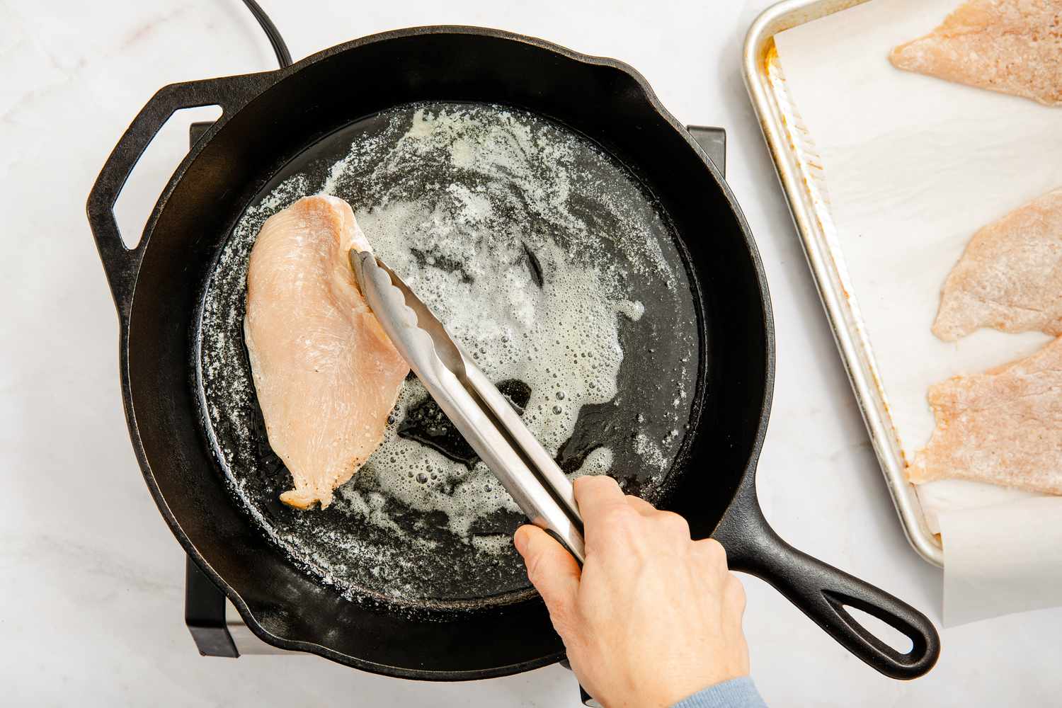 dredged chicken seared on a cast iron skillet for chicken marsala recipe