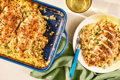 no-peek chicken in a casserole dish at a table setting with a serving on a plate, a glass of water, glasses, and a table napkin
