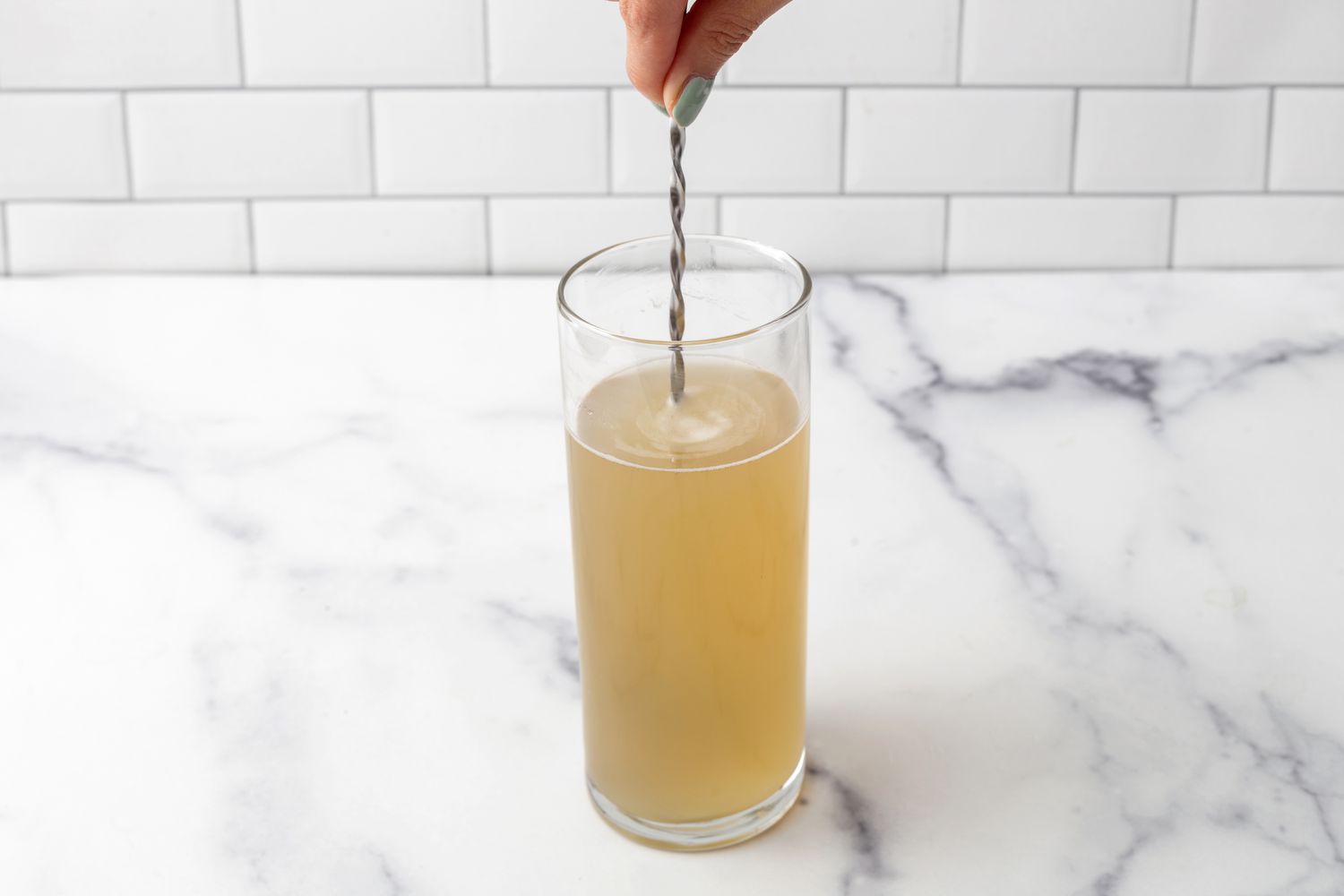 Stirring a ginger drink with a cocktail spoon.