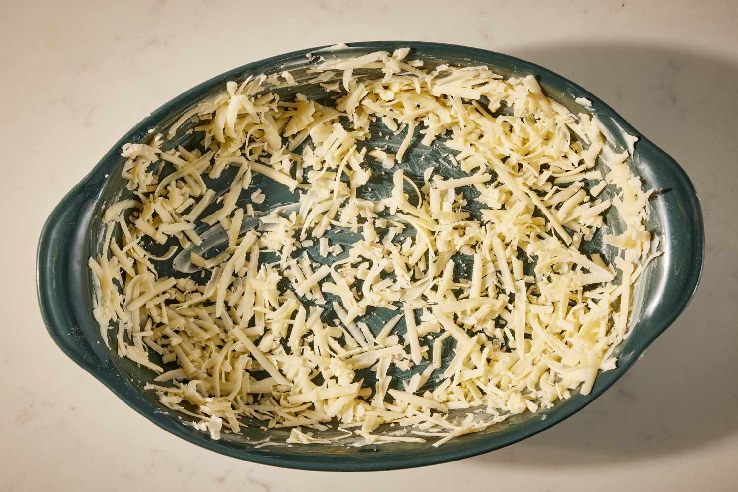 Overhead view of a green casserole dish with the cheese spread around the surface for Wisconsin Stuffing recipe