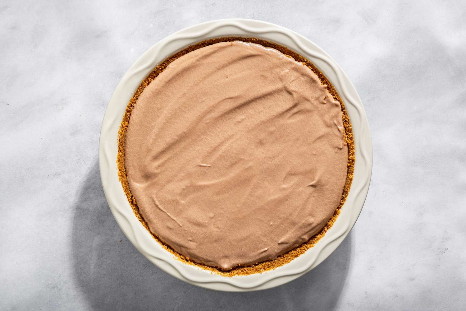 A pie in a round dish with a smooth filling and a crumb crust