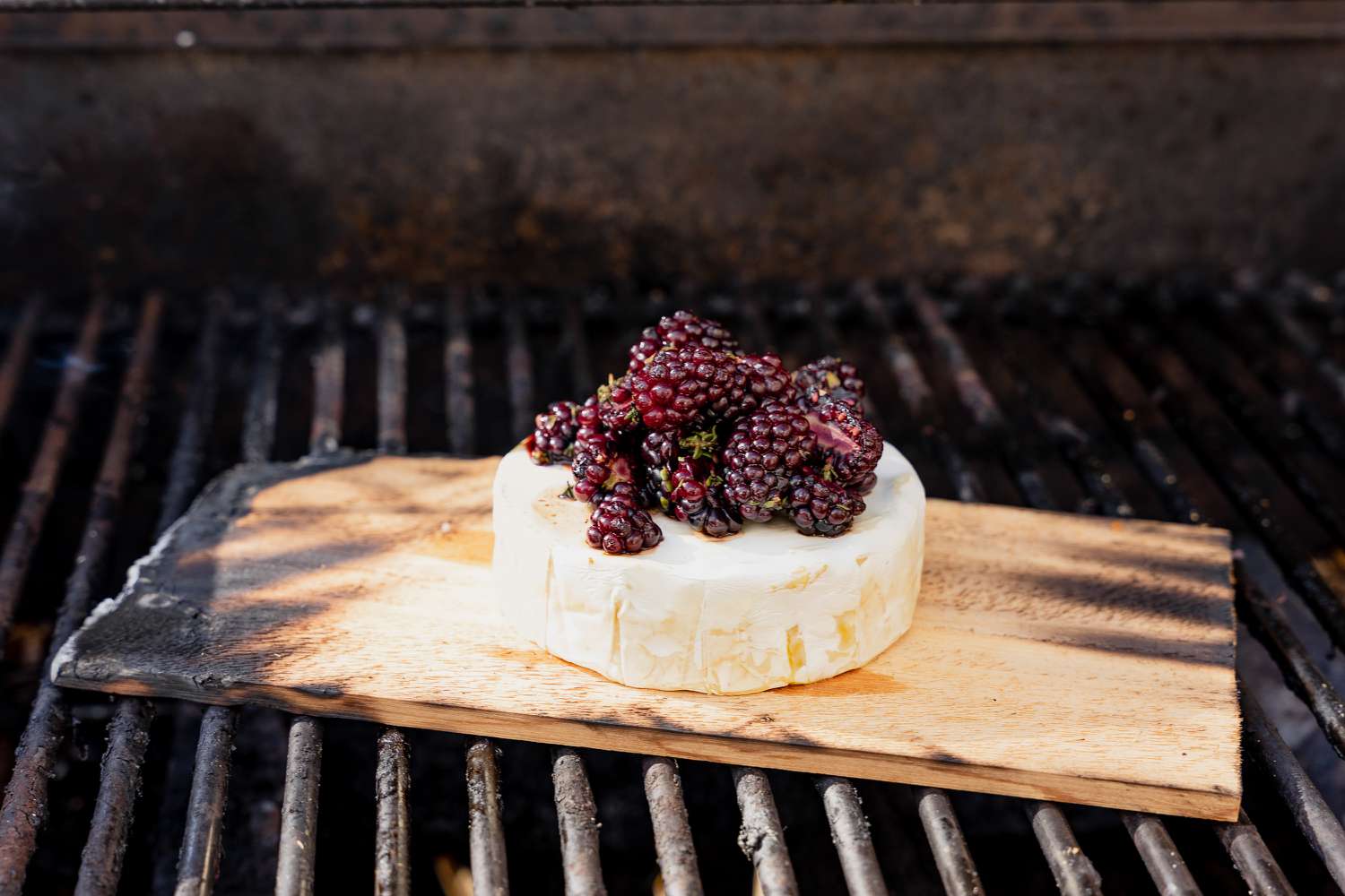 Circle of Brie Topped With Halved Blackberries on a Cedar Plank on the Grill