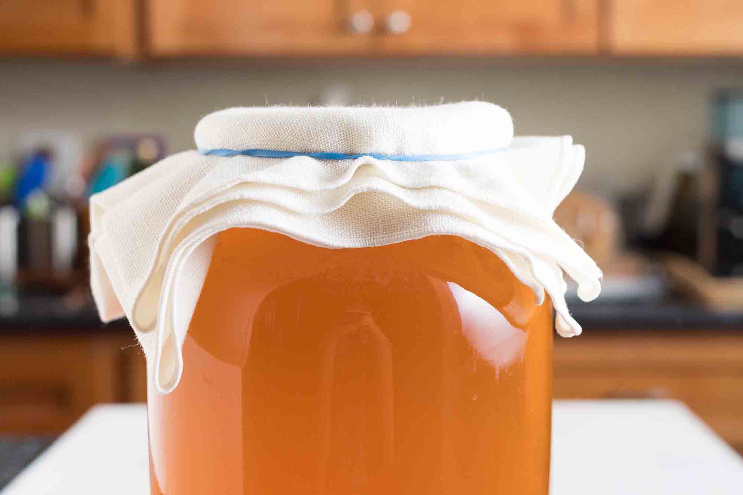 Covered jar of homemade kombucha on a counter