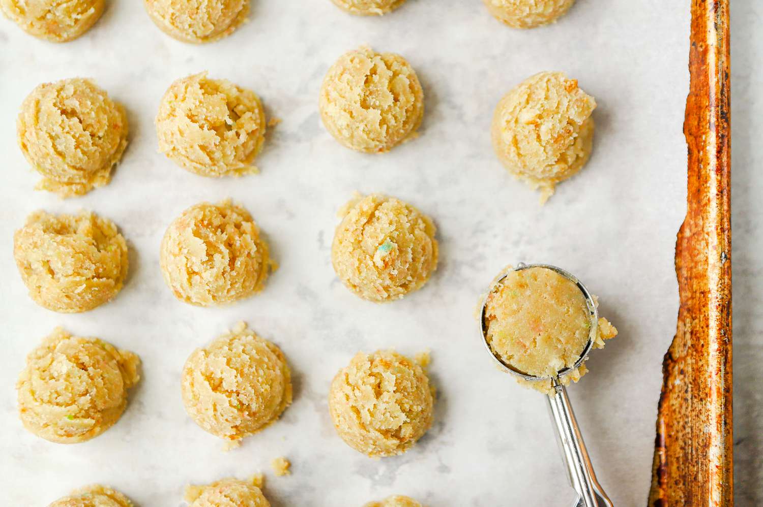 Cake Pop Dough Balls Sitting on a Baking Pan Covered with Parchment Made Using an Cookie Scoop