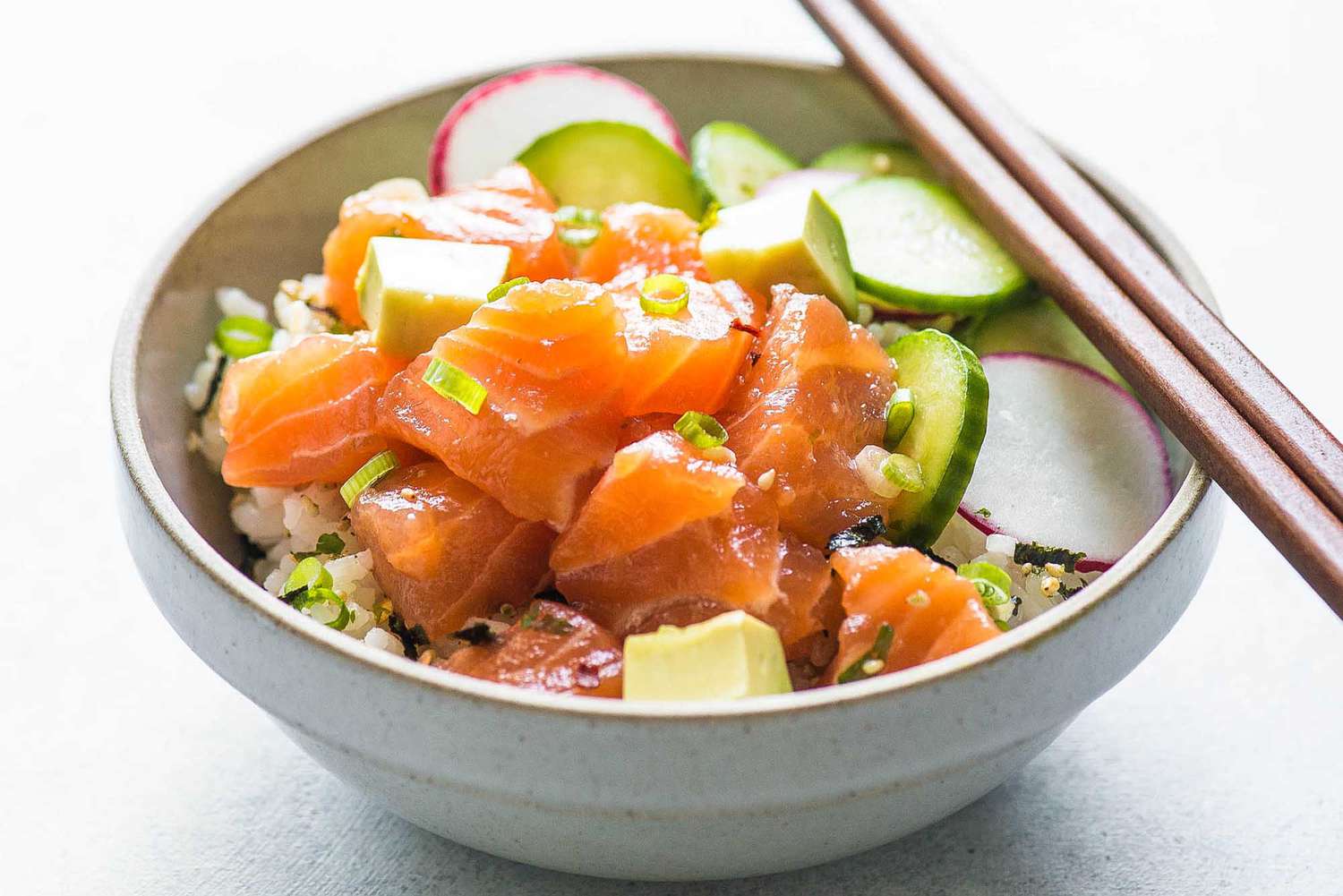 avocado salmon poke bowl with chopsticks
