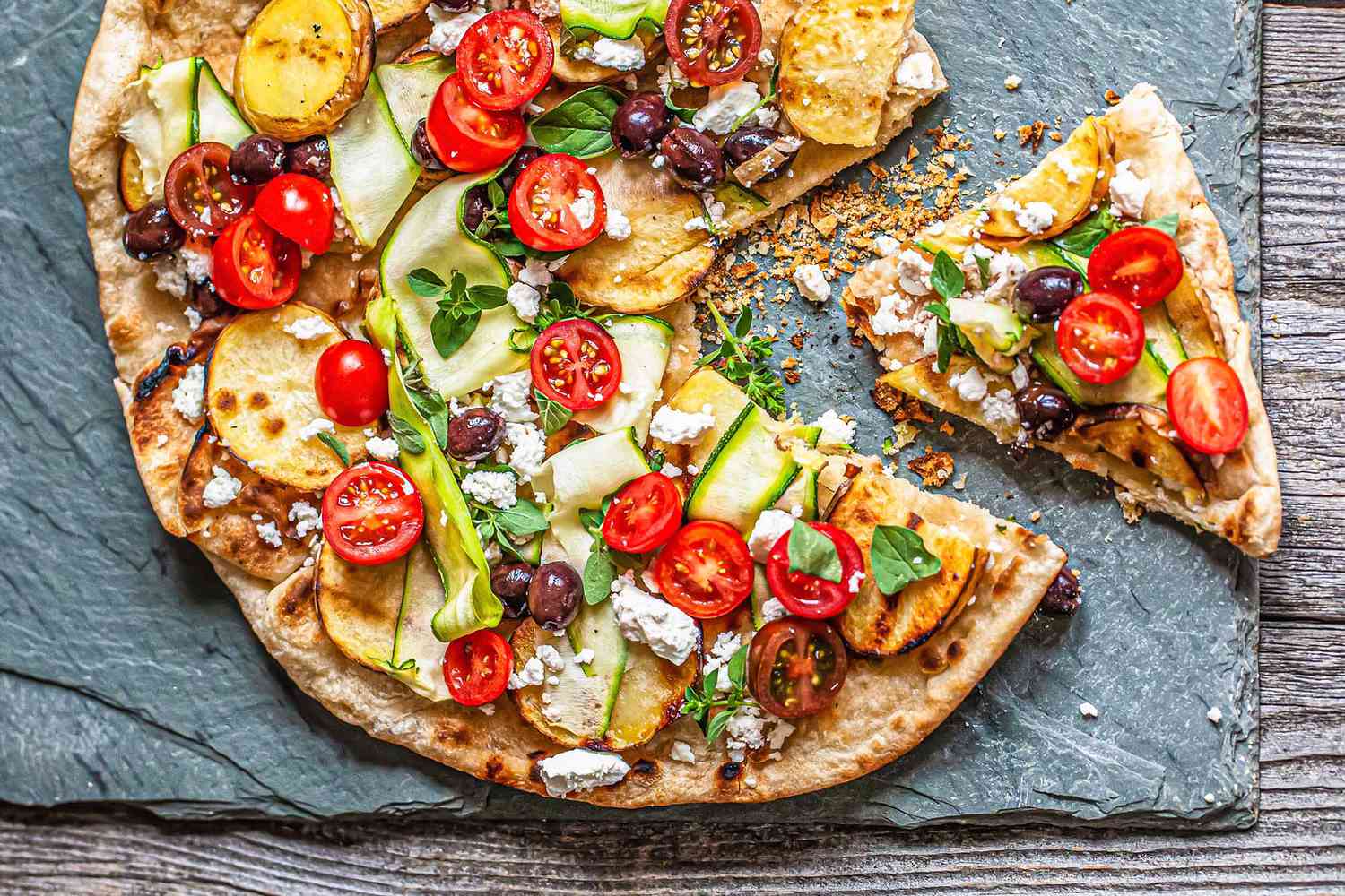 Grilled Greek pizza on a baking stone.