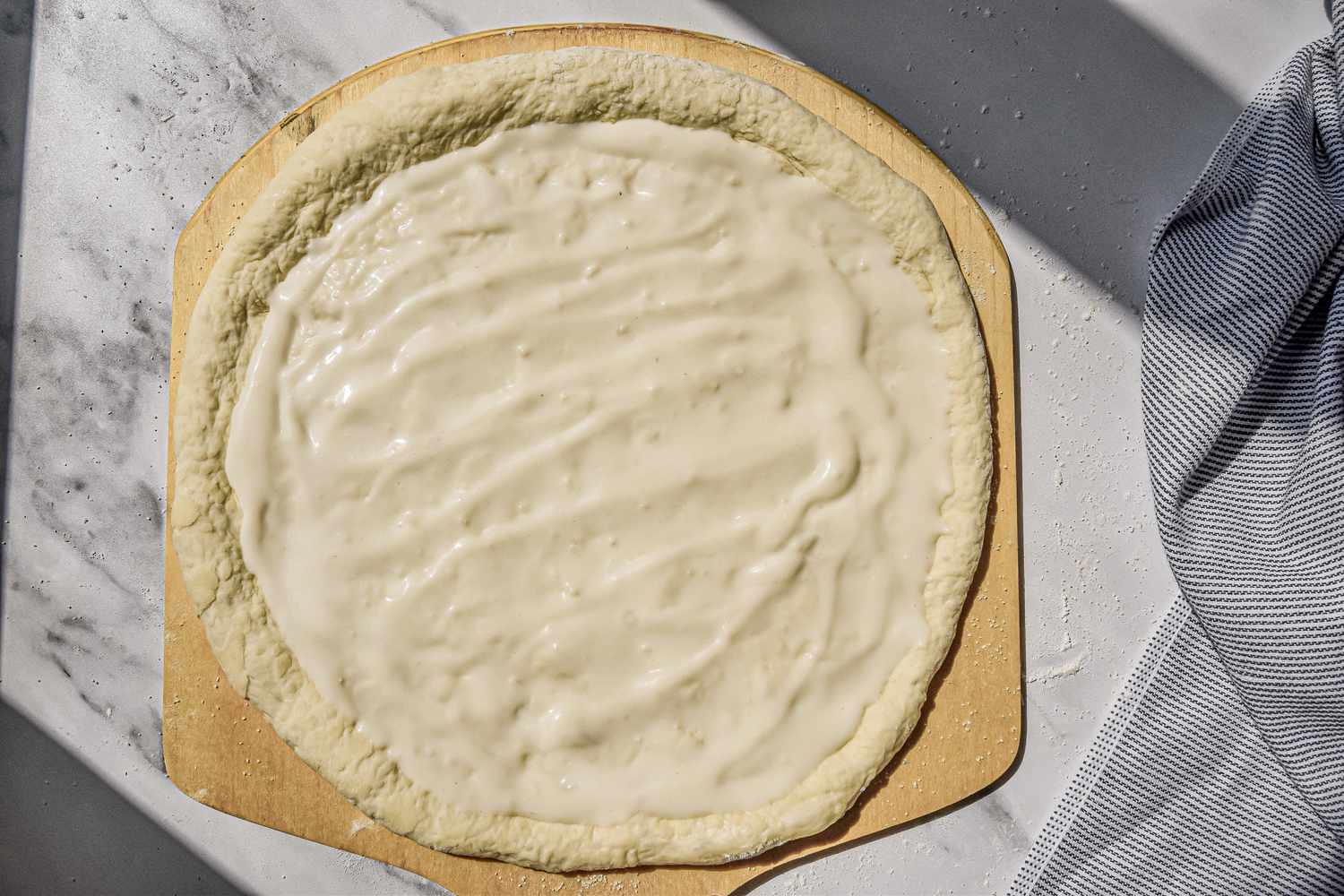 Alfredo Sauce Added to Pizza Dough up to the Crust Ridge