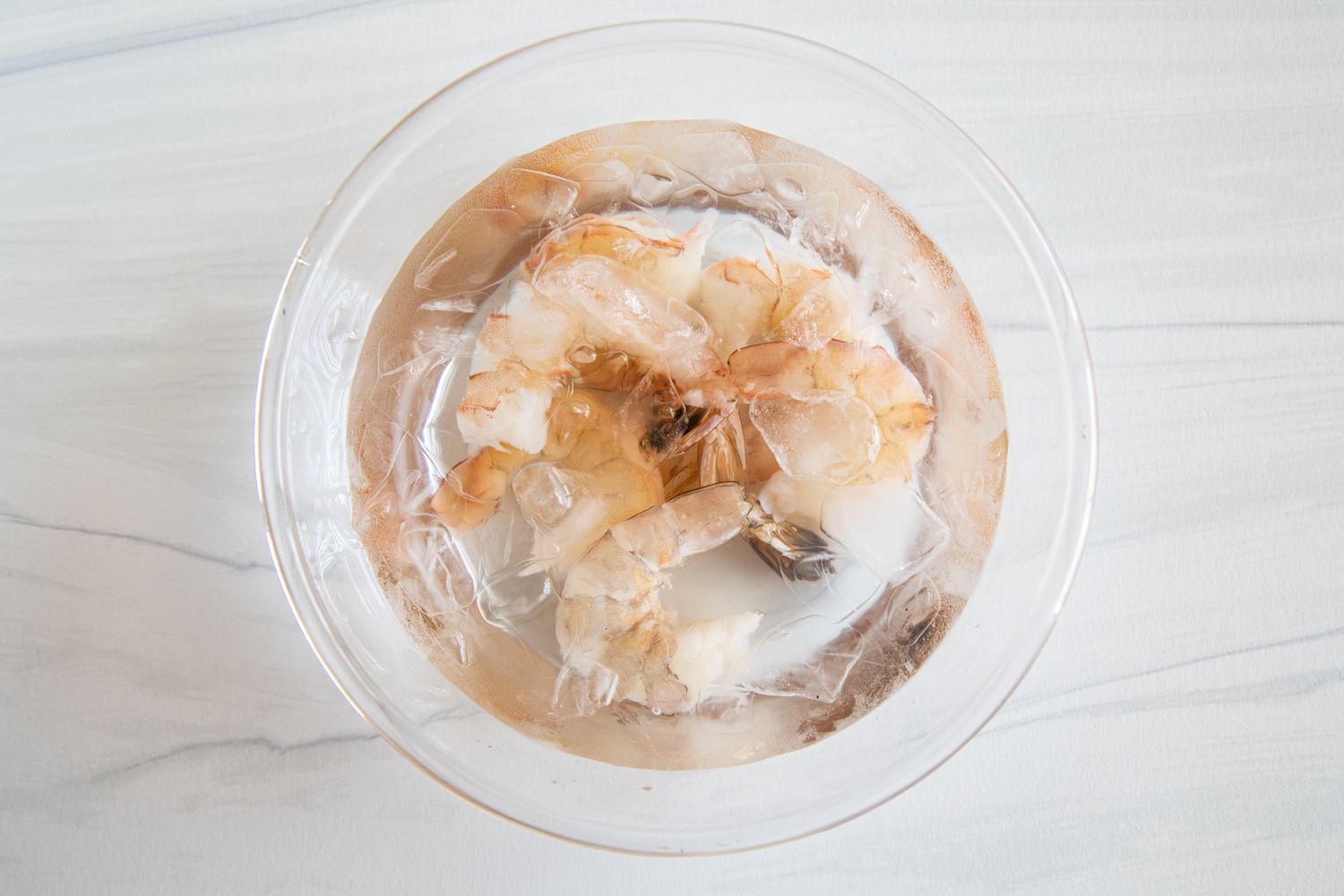 A bowl of ice water with deveined shrimp showing how to clean a shrimp.