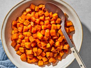 Small cubes of roasted sweet potato in a serving bow, with a serving spoon