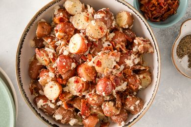 A bowl of potato salad topped with crumbled bacon