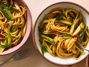 Two bowls of scallion pasta on a table, with forks nearby