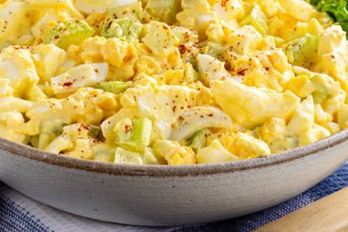 A bowl of egg salad garnished with paprika served in a ceramic dish