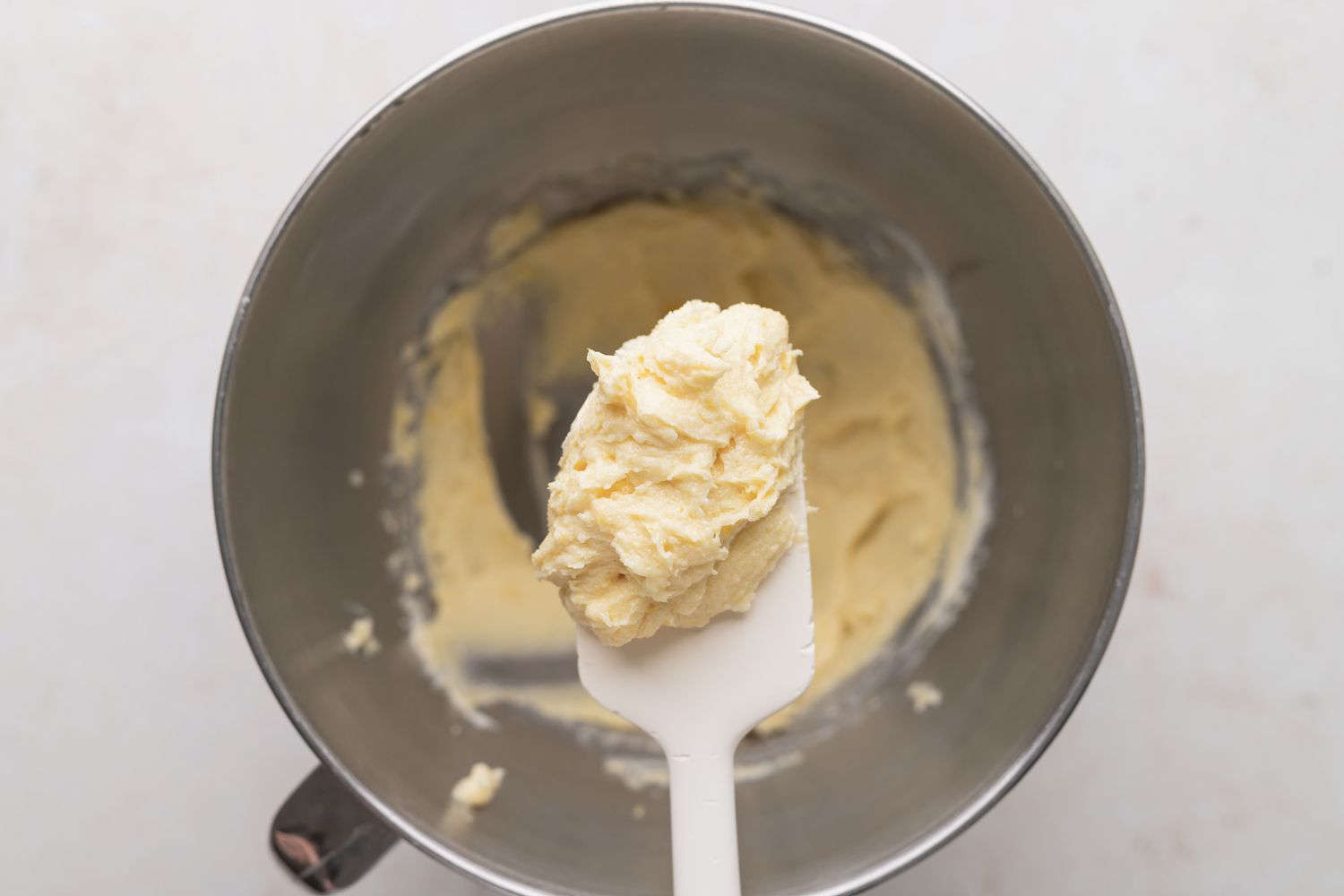 Spatula holding up batter to make jam filled sandwich cookies.