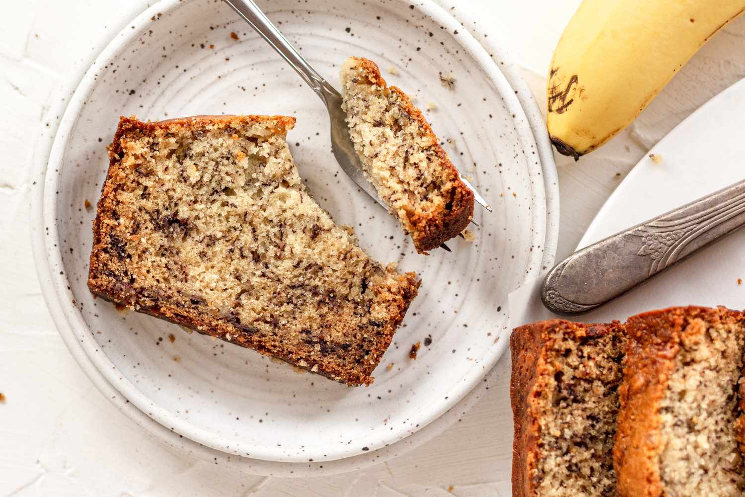 Overhead view of a slice of banana bread on a plate.