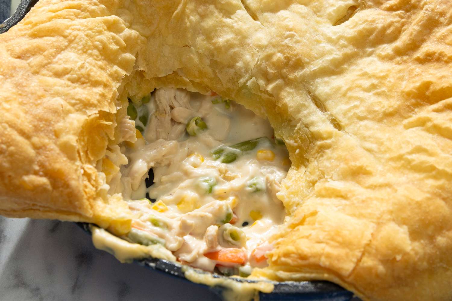Chicken pot pie with a flaky crust revealing a creamy filling with vegetables and chicken