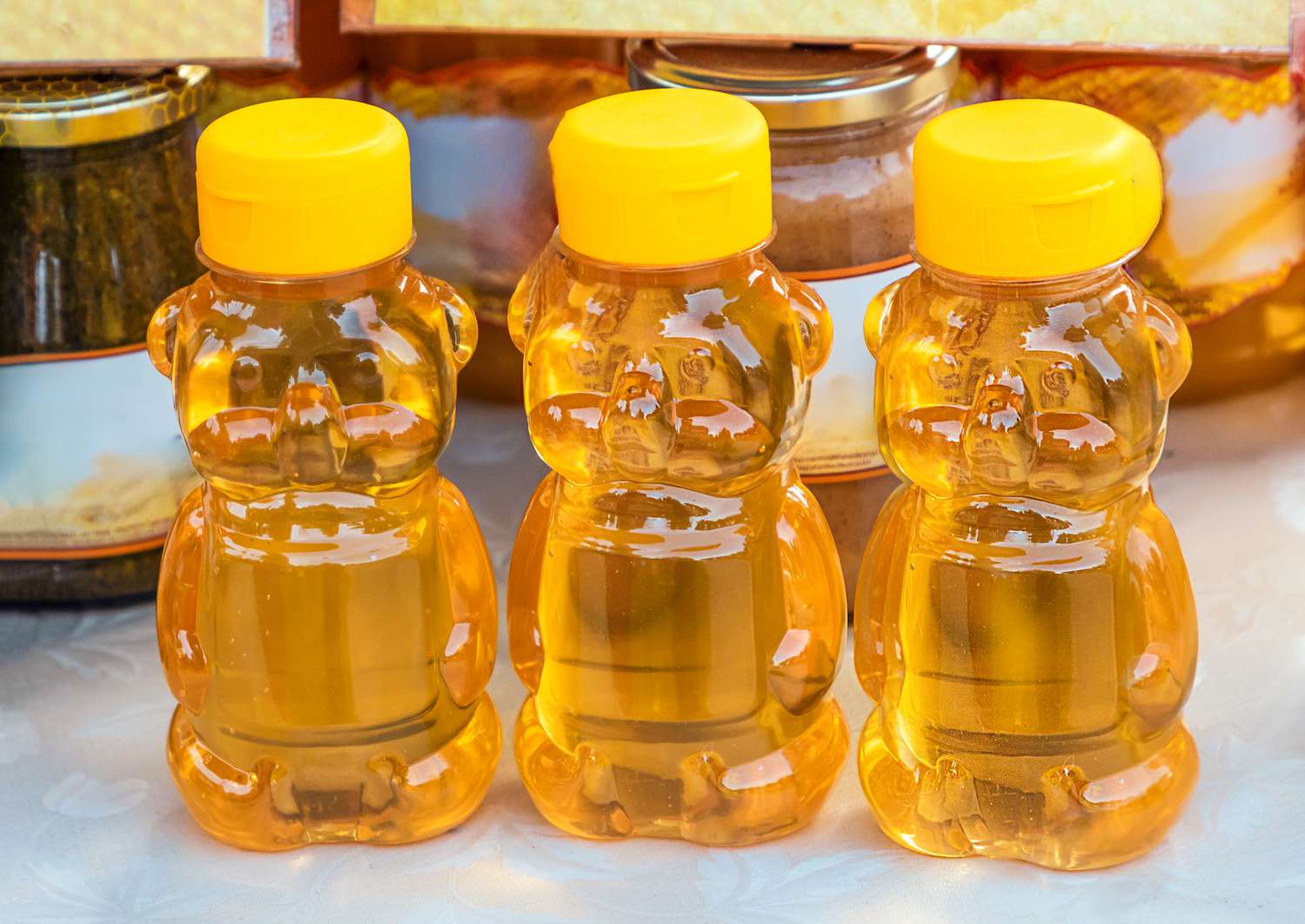 jars of honey on a table and in the background, jars of jam