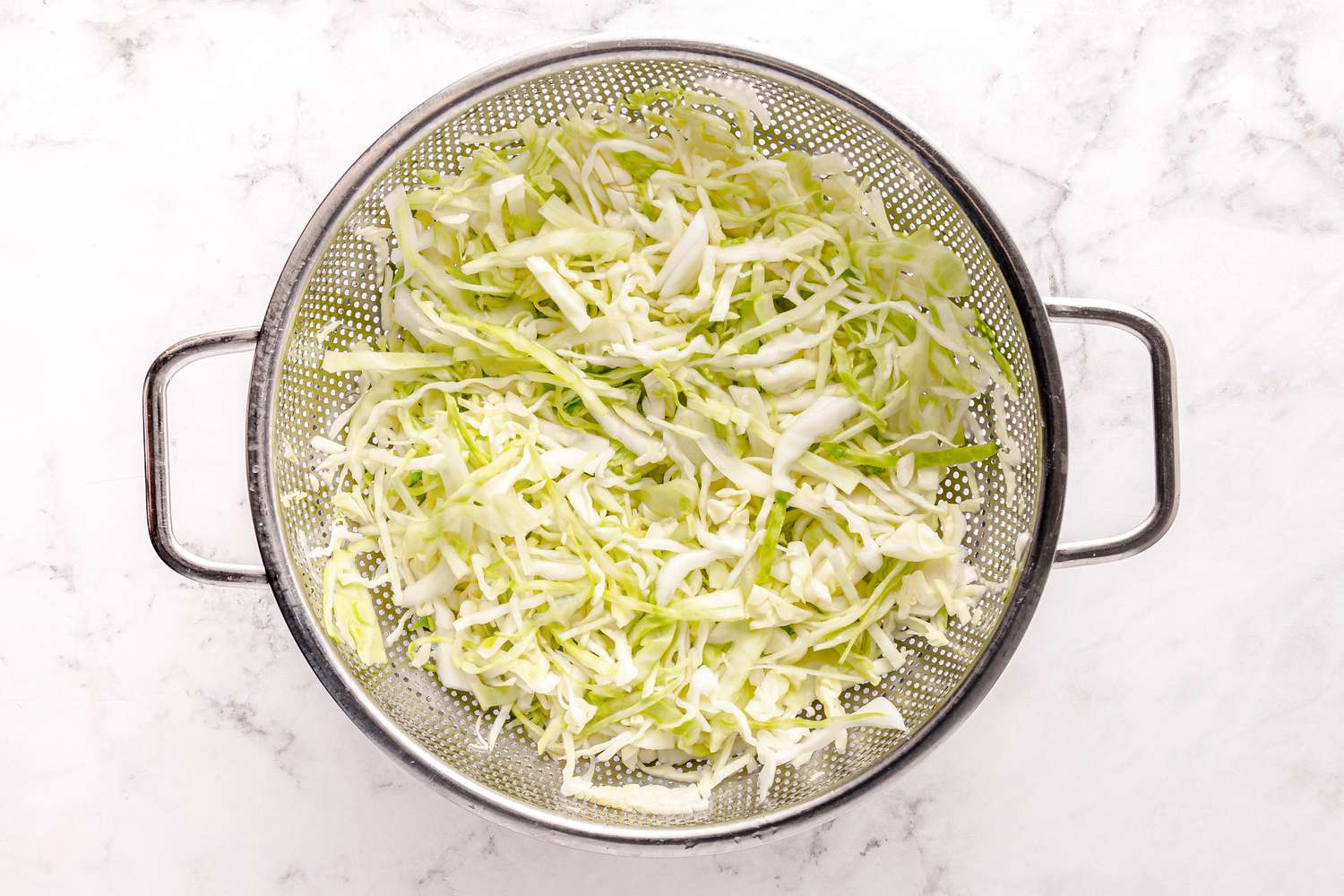 Shredded Cabbage in a Colander for Curtido Recipe