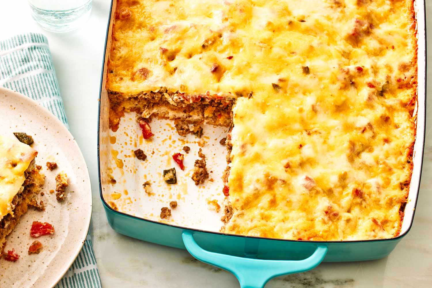 Cattle Drive Casserole in a large dish with a slice cut out of it, slice on a plate to the side with a napkin