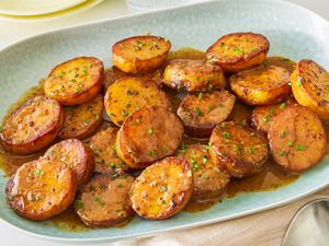 Baked sliced miso melting potatoes in a light blue serving plate, dressed in a miso sauce