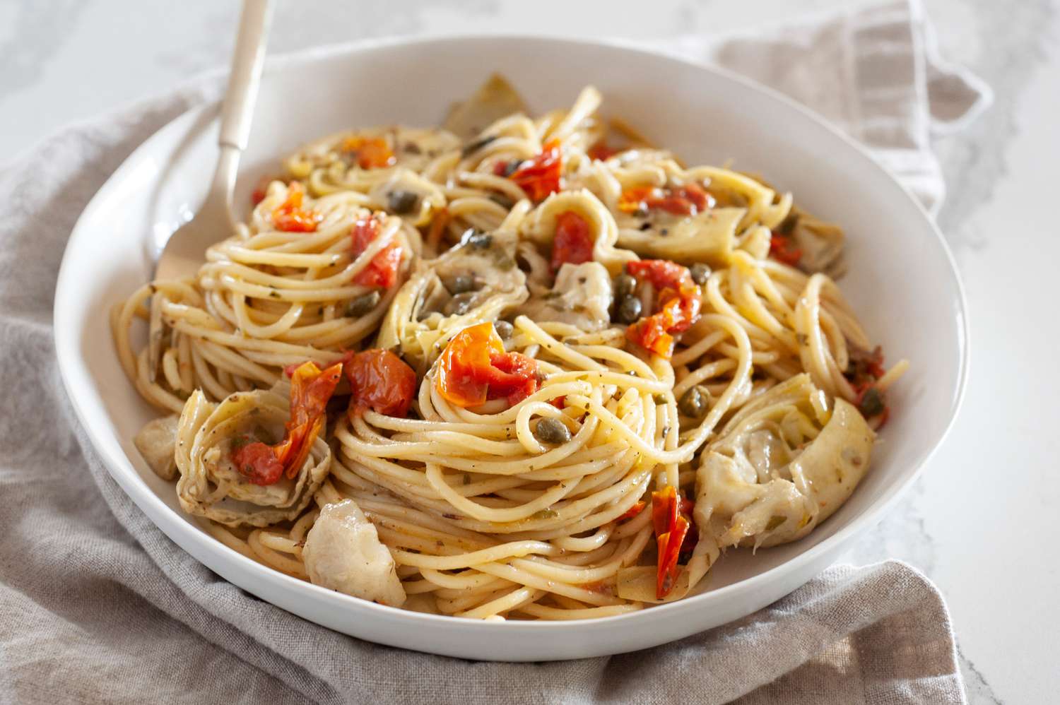 One-Pot Spaghetti with Tomatoes, Artichokes, and Capers in a Bowl