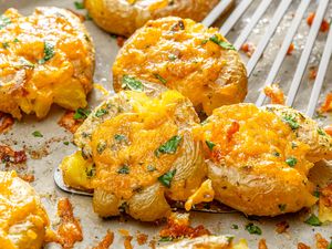 Cheesy baked smashed potatoes topped with herbs