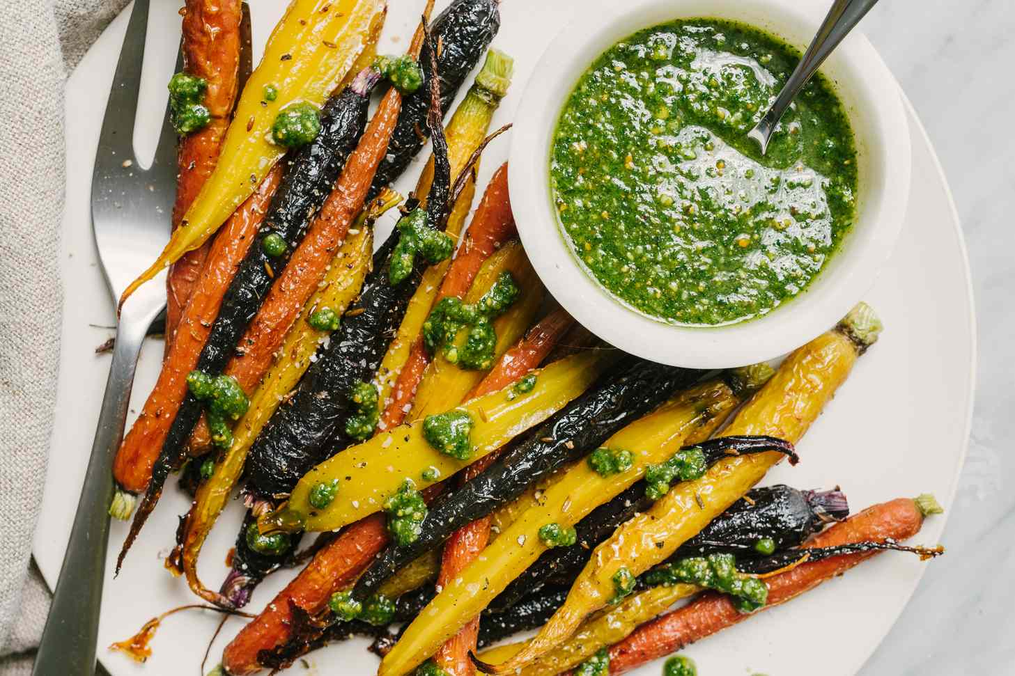 Roasted assorted carrots with a side of green pesto sauce in a bowl