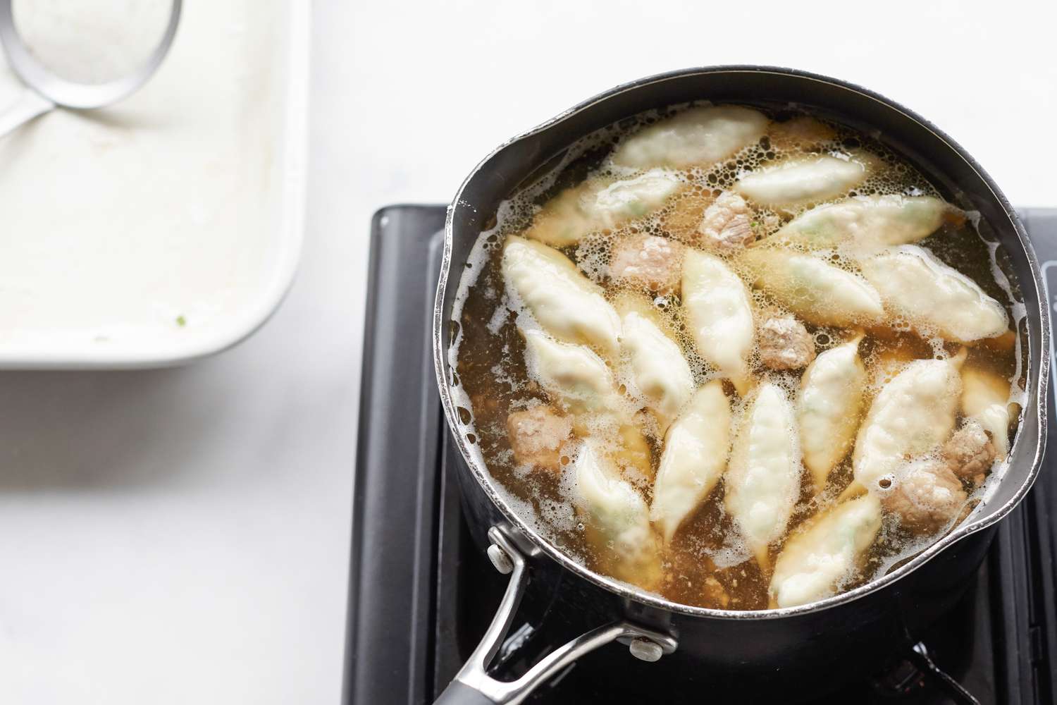 Making Korean dumpling beef soup in a pot on the stove.