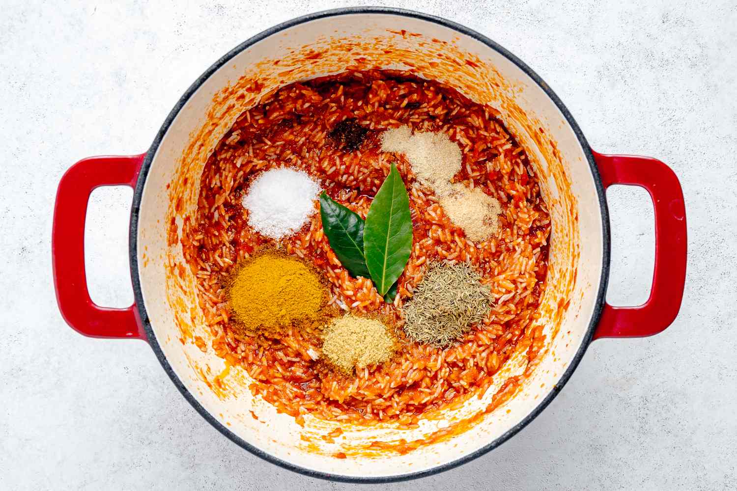 Rice and Spices Added to Stew Base in the Dutch Oven for Jollof Rice Recipe