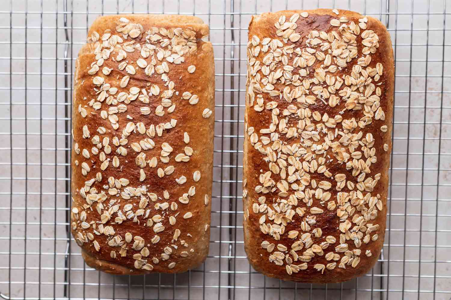 Two loaves of homemade oatmeal bread cooling on a rack.