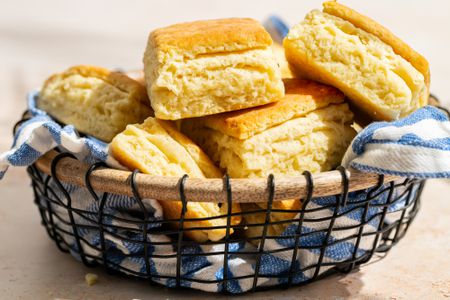 Metal mesh basket of Mayonnaise Biscuits with a blue and white checkered cloth napkin