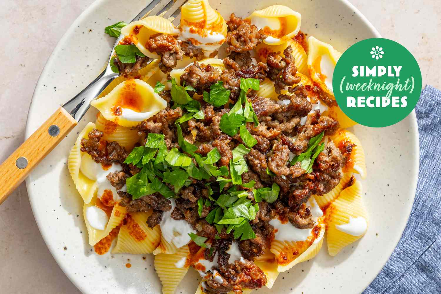 A plate of pasta shells topped with ground meat and garnished with parsley with the label Simply Recipes Weeknight visible