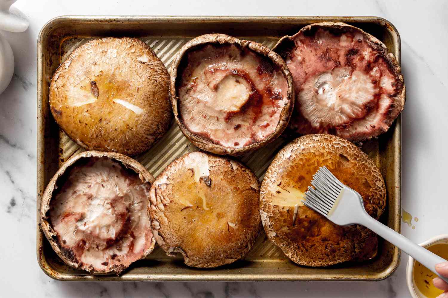 Portobello Mushrooms Brushed With Oil While Resting in a Small Baking Sheet for Grilled Mushroom Pizza Recipe