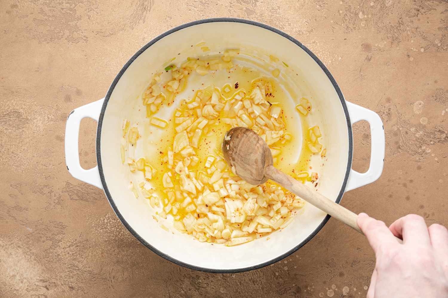 Aromatics Stirred in the Dutch Oven Using a Wooden Spoon for Creamy White Bean Soup Recipe