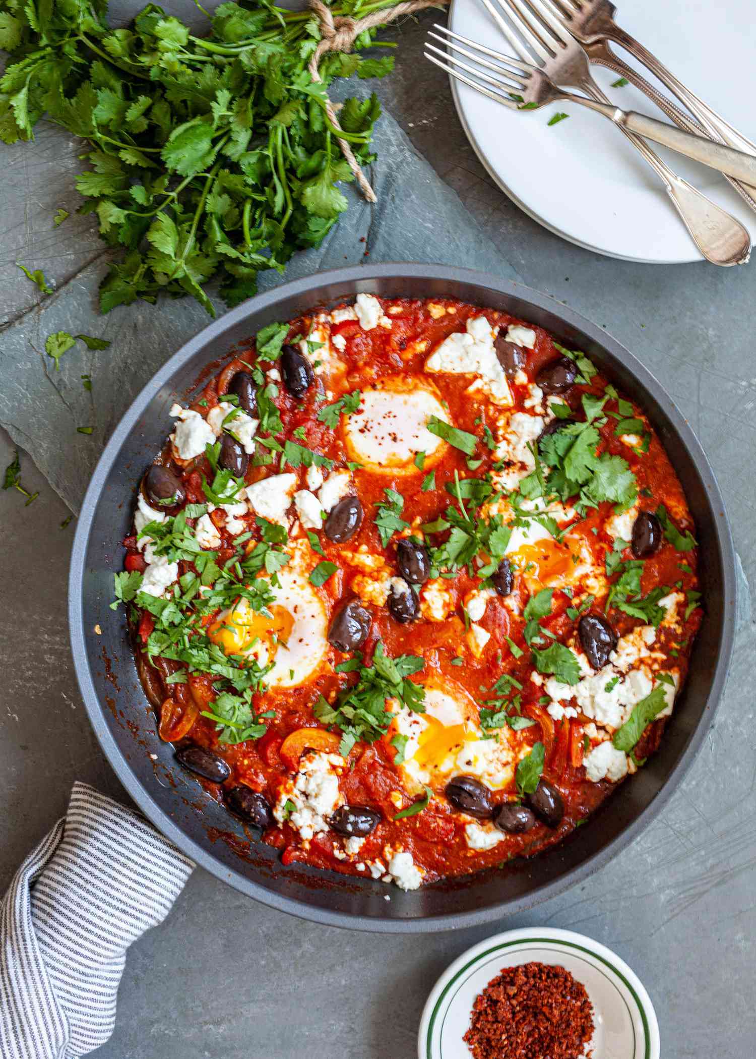 Shakshouka in a skillet with cilantro next to it.
