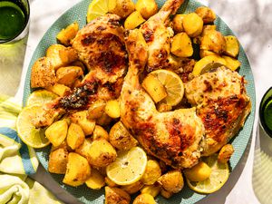A large plate of Greek-style roast chicken with potaotes and lemon slices