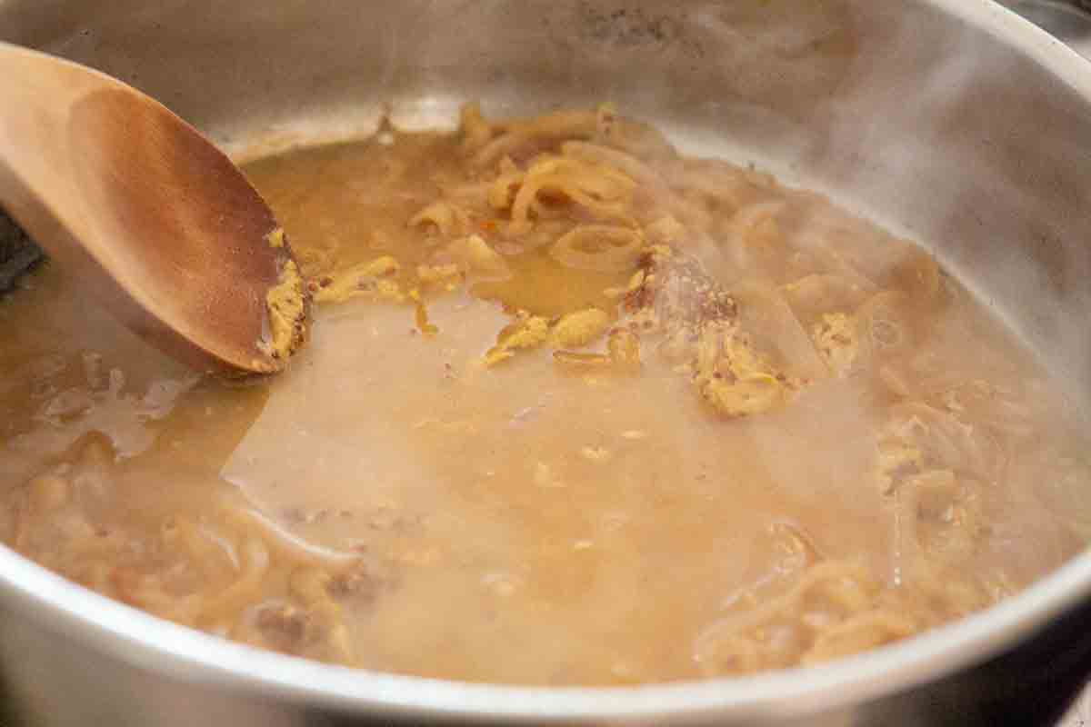 dijon sauce being cooked in pan with shallots