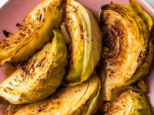 Overhead view of 6 wedges of melting cabbage on a pink plate