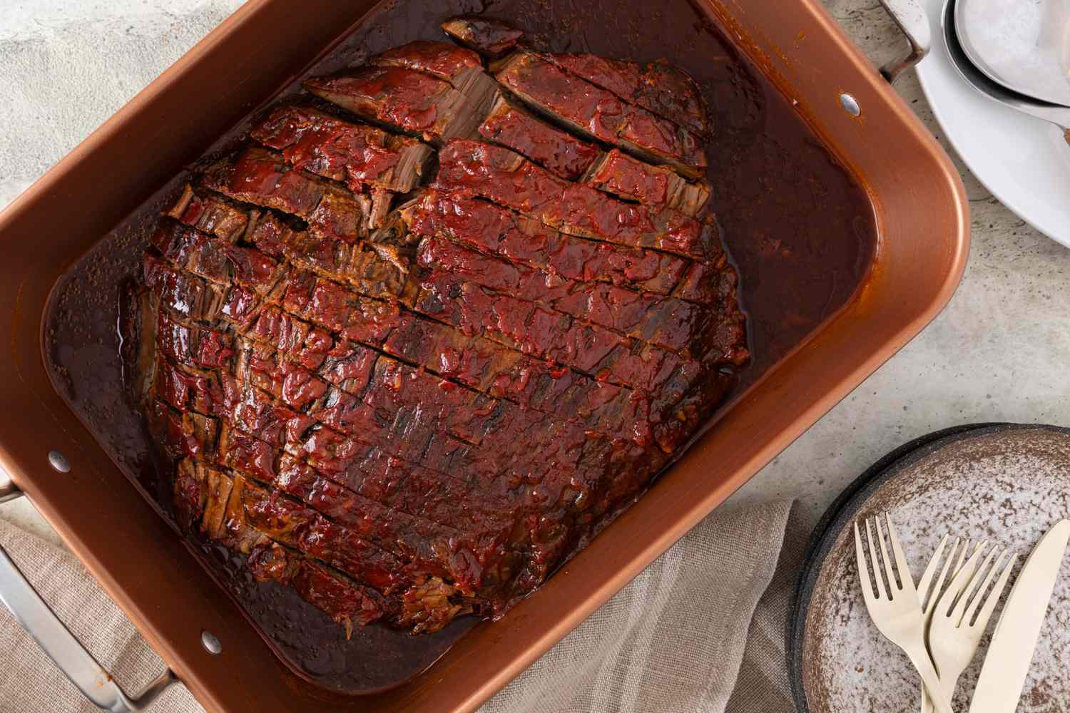 A sliced brisket in a bronze roasting pan