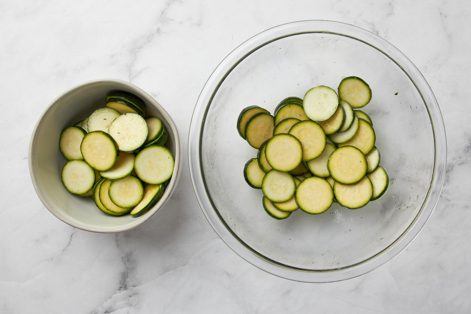 Zucchini slices in a clear bowl with some in a smaller bowl off to the side