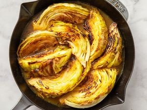 Cooked wedges of cabbage arranged in a skillet
