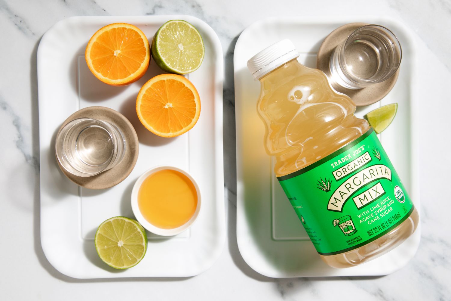 Two trays one with sliced citrus and spirits the other with a bottle of organic margarita mix and lime