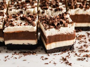 Layered dessert squares with chocolate cream and a cookie base topped with chocolate shavings