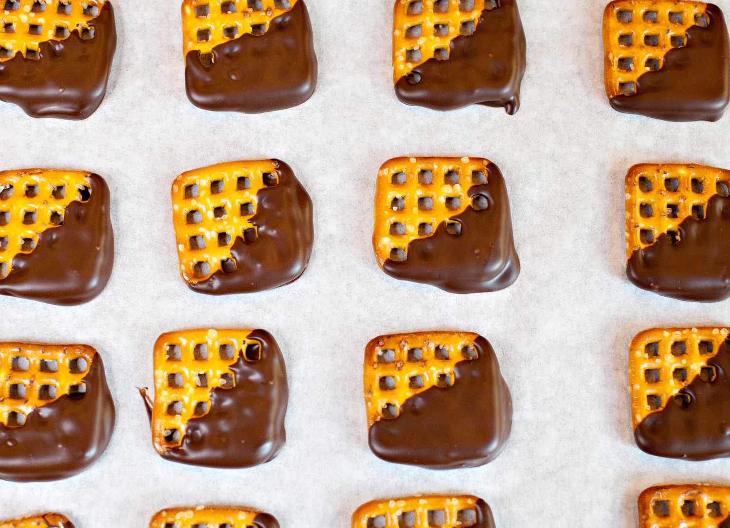 Pretzels Dipped in Chocolate on a Parchment Paper Lined Baking Sheet for How to Temper Chocolate