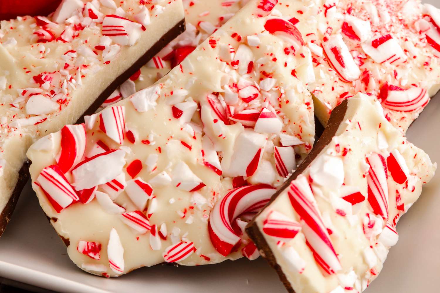 Chocolate peppermint bark candy on white plate with red snowflake mug filled with hot cocoa for Santa