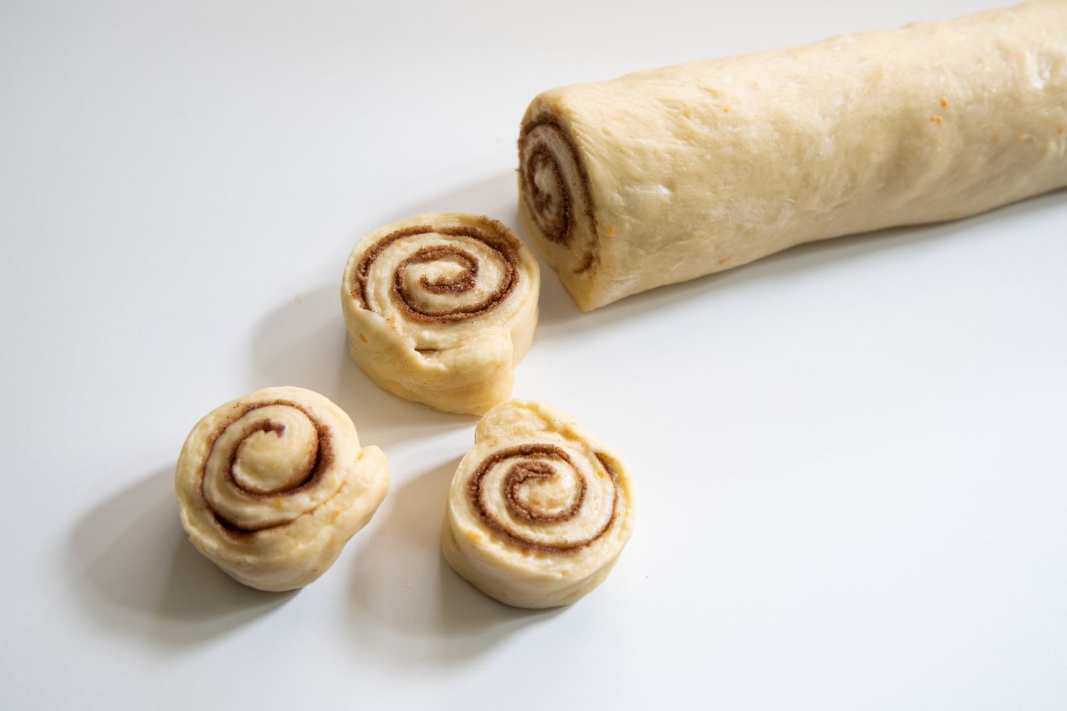 Rolled dough for a cinnamon bun recipe cut into slices.