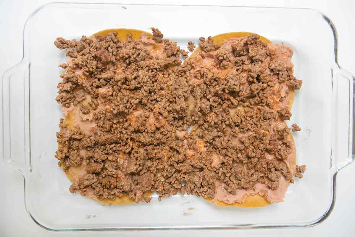 To make mexican lasagna, add a layer of ground beef on top of the beans
